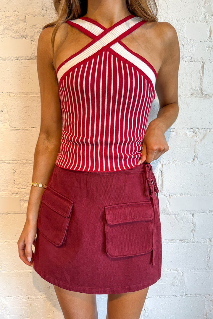 Red and white striped top with a maroon skirt against a light brick wall.