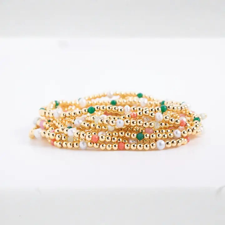 Set of gold beaded bracelets with multicolored beads on a white background